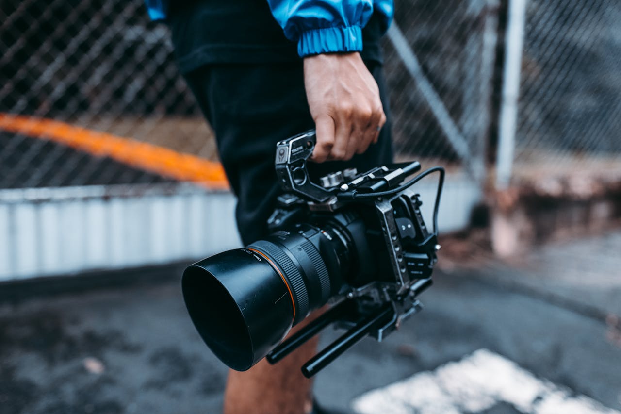 Focused image of a person holding a professional film camera outdoors.